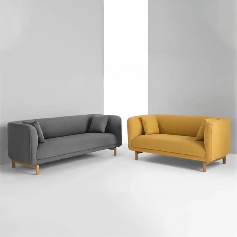 curved fabric sofa with soft wraparound arms, deep cushioning and raised wooden legs — room setting showing the relaxed se...