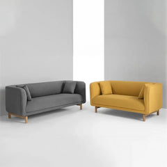 curved fabric sofa with soft wraparound arms, deep cushioning and raised wooden legs — room setting showing the relaxed se...