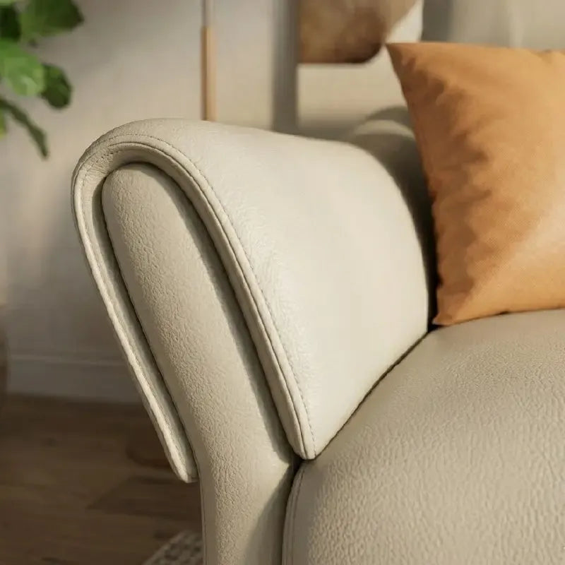 beige leatherette sofa with supportive high back cushions, rounded arms and slim raised legs — front view in a bright livi...