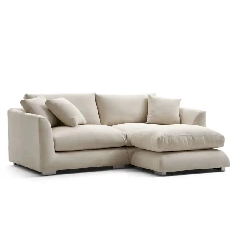 wide l shape fabric sofa with rounded arms, loose back cushions and deep comfortable seating — wide room view showing the...