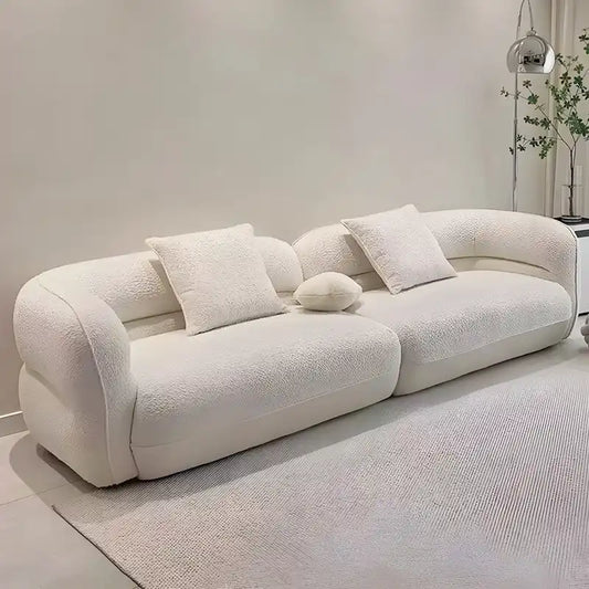 low lounge sofa with thick cushions, loose back pillows and soft rounded edges — front view in a bright living room