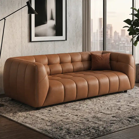 warm brown luxury sofa with deep square cushioning, rounded edges and a low relaxed shape — front view in a bright living...