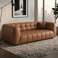 warm brown luxury sofa with deep square cushioning, rounded edges and a low relaxed shape — front view in a bright living...
