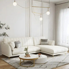 soft cream corner sofa with deep cushions, vertical back details and slim gold finish legs — front view in a bright living...