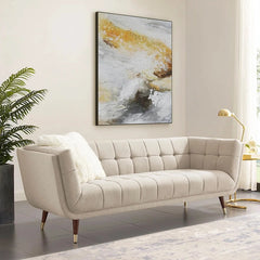 beige fabric sofa with soft curved arms, square cushion details and raised wooden legs — front view in a bright living room