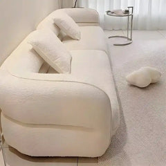 low lounge sofa with thick cushions, loose back pillows and soft rounded edges — angled view showing the full shape and cu...