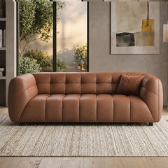 warm brown luxury sofa with deep square cushioning, rounded edges and a low relaxed shape — angled view showing the full s...