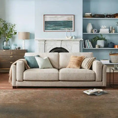 modern neutral fabric sofa with wide padded arms, thick cushions and clean straight lines — angled view showing the full s...