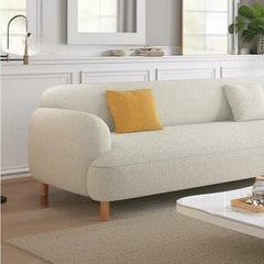 rounded fabric sofa with deep cushions, soft wide arms and a clean modern finish — side angle showing the arms and raised...