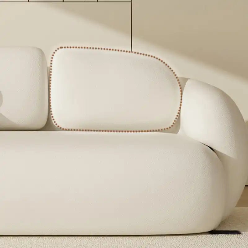 soft curved fabric sofa with cloud like cushions, wraparound arms and a low grounded base — side angle showing the arms an...