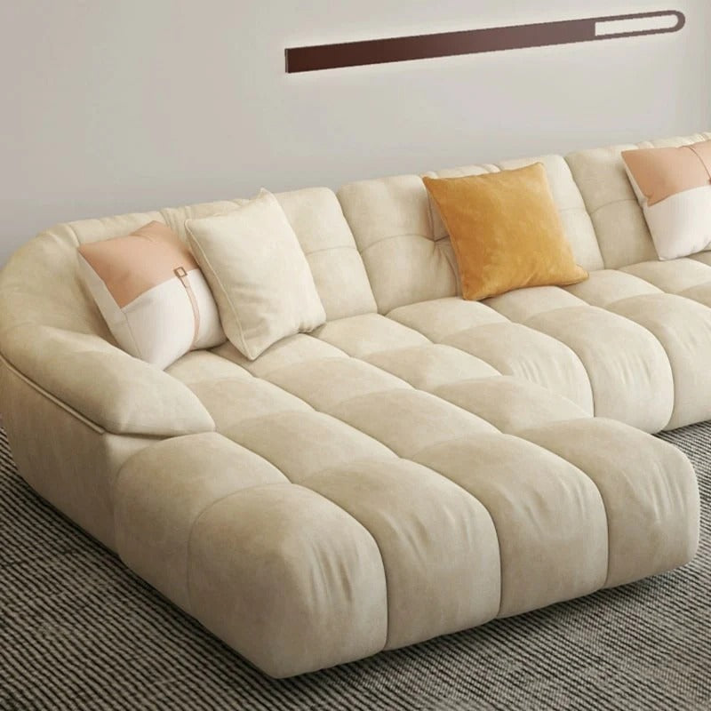 cream l shape sofa with deep soft cushions, rounded arms and a cosy low base — side angle showing the arms and raised base