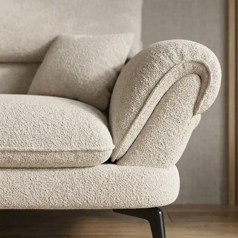 cream textured fabric sofa with curved arms, supportive back cushions and slim dark legs — close view showing the cushion...