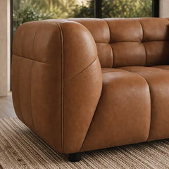 warm brown luxury sofa with deep square cushioning, rounded edges and a low relaxed shape — wide room view showing the com...