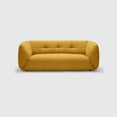 warm mustard rounded sofa with deep square cushioning and a soft textured finish — room setting showing the relaxed seatin...