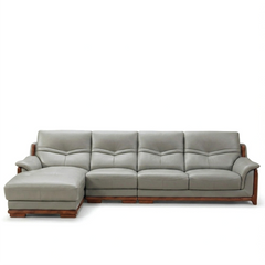 corner sofa with deep cushions, rounded arms and warm polished wooden side details — angled view showing the full shape an...