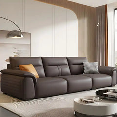 dark brown luxury sofa with broad pillow soft arms, cushioned back and detailed side panels — front view in a bright livin...
