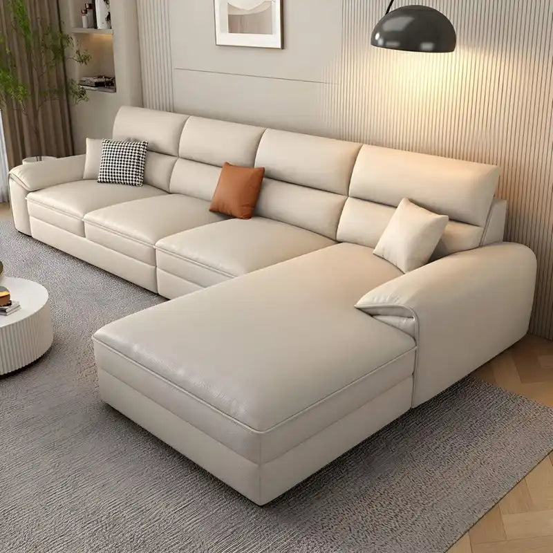 beige l shape leatherette sofa with deep seating, high back cushions and wide padded arms — front view in a bright living...