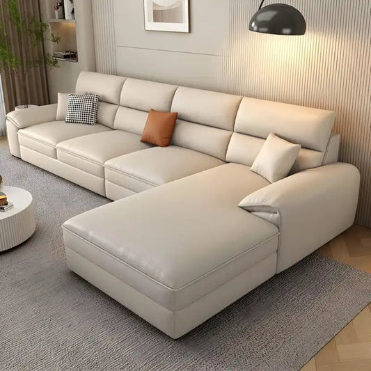 beige l shape leatherette sofa with deep seating, high back cushions and wide padded arms — front view in a bright living...