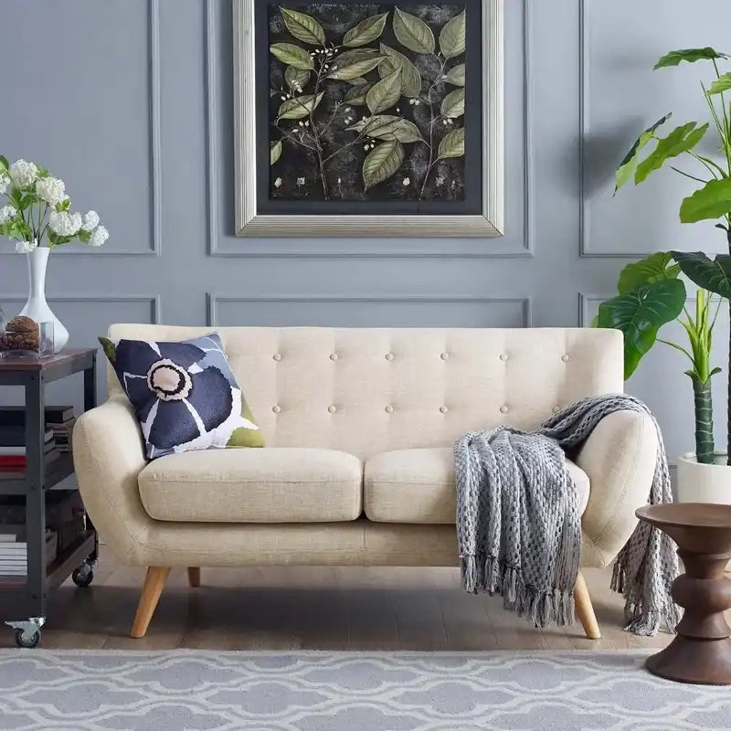 soft beige fabric sofa with rounded arms, buttoned back cushions and slim wooden legs — front view in a bright living room