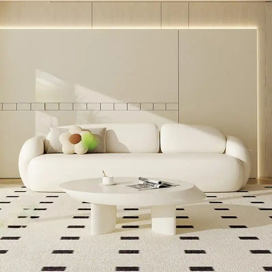 soft curved fabric sofa with cloud like cushions, wraparound arms and a low grounded base — front view in a bright living...