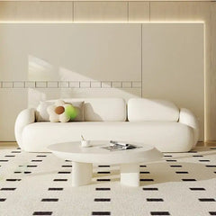 soft curved fabric sofa with cloud like cushions, wraparound arms and a low grounded base — front view in a bright living...