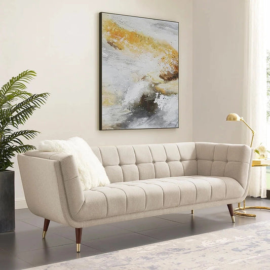 beige fabric sofa with soft curved arms, square cushion details and raised wooden legs — front view in a bright living room