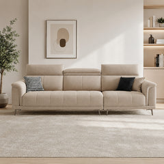 beige l shape sofa with adjustable head support, rounded arms and slim raised legs — angled view showing the full shape an...