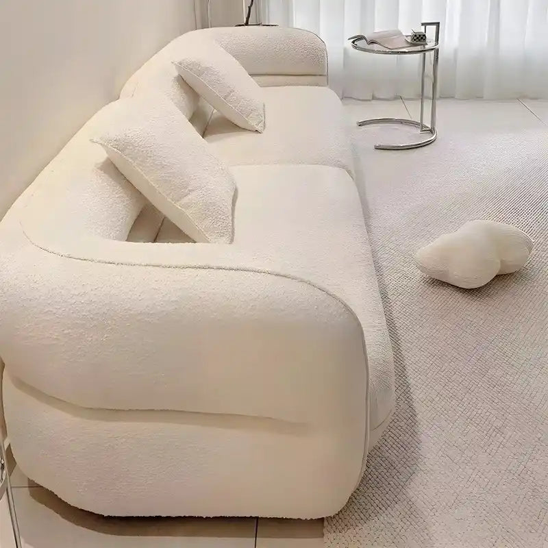 low lounge sofa with thick cushions, loose back pillows and soft rounded edges — angled view showing the full shape and cu...