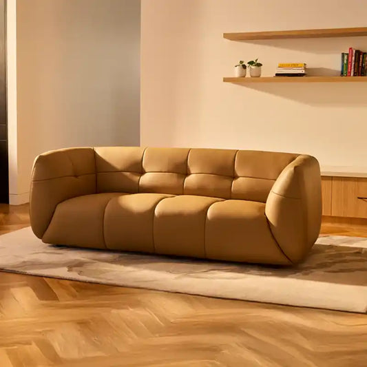 warm mustard rounded sofa with deep square cushioning and a soft textured finish — angled view showing the full shape and...