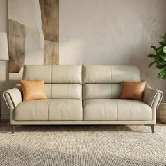 beige leatherette sofa with supportive high back cushions, rounded arms and slim raised legs — angled view showing the ful...