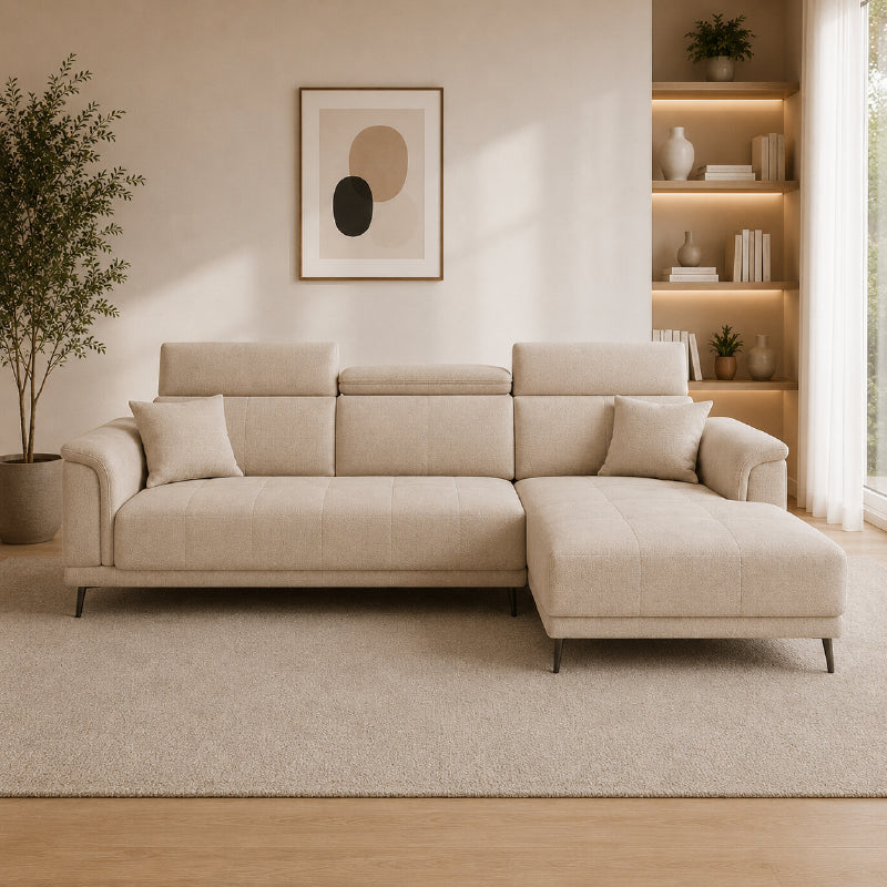 beige l shape sofa with adjustable head support, rounded arms and slim raised legs — close view showing the cushion and su...