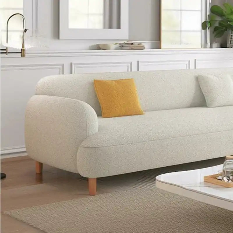 rounded fabric sofa with deep cushions, soft wide arms and a clean modern finish — side angle showing the arms and raised...