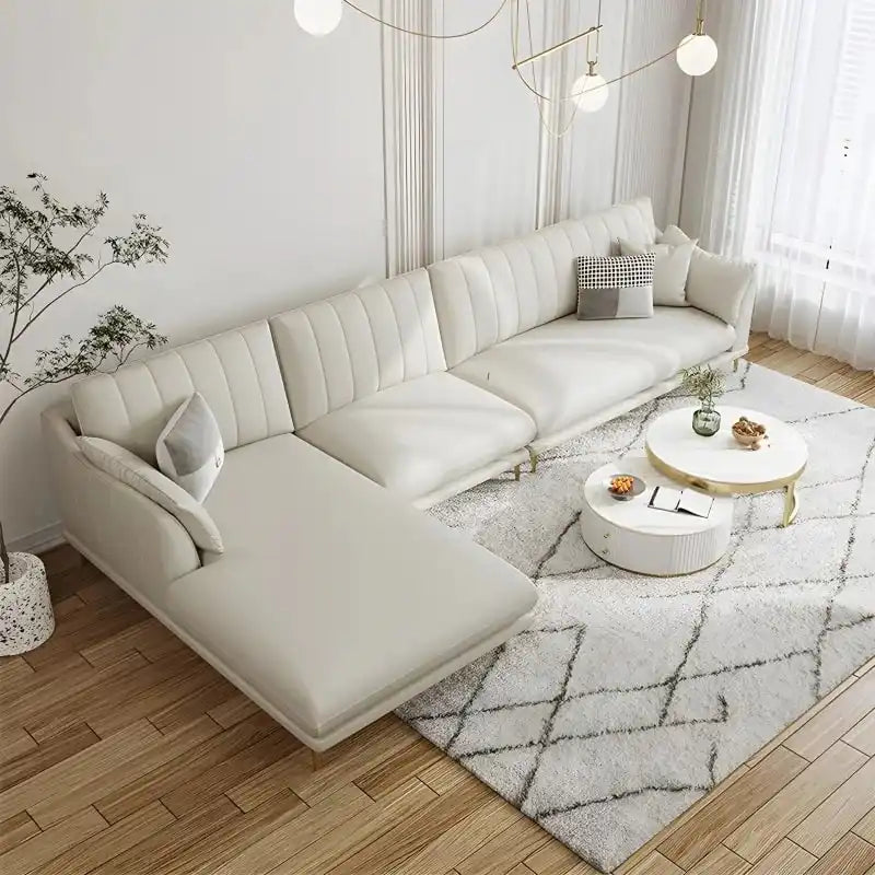 soft cream corner sofa with deep cushions, vertical back details and slim gold finish legs — side angle showing the arms a...