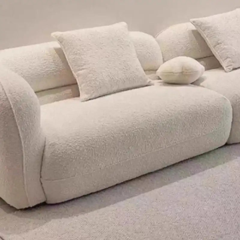 low lounge sofa with thick cushions, loose back pillows and soft rounded edges — side angle showing the arms and raised base