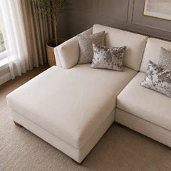 beige corner sofa with a compact l shape, soft cushions and a smooth fabric finish — side angle showing the arms and raise...
