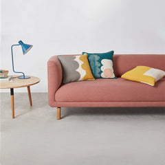curved fabric sofa with soft wraparound arms, deep cushioning and raised wooden legs — side angle showing the arms and rai...