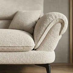 cream textured fabric sofa with curved arms, supportive back cushions and slim dark legs — close view showing the cushion...