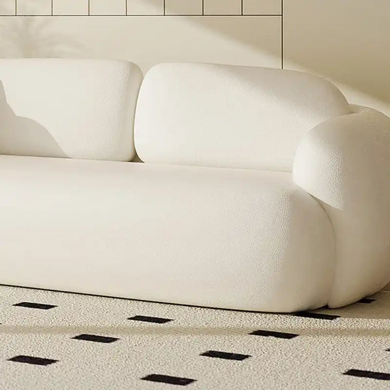 soft curved fabric sofa with cloud like cushions, wraparound arms and a low grounded base — close view showing the cushion...