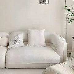 low lounge sofa with thick cushions, loose back pillows and soft rounded edges — close view showing the cushion and surfac...