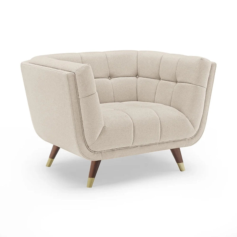 beige fabric sofa with soft curved arms, square cushion details and raised wooden legs — close view showing the cushion an...