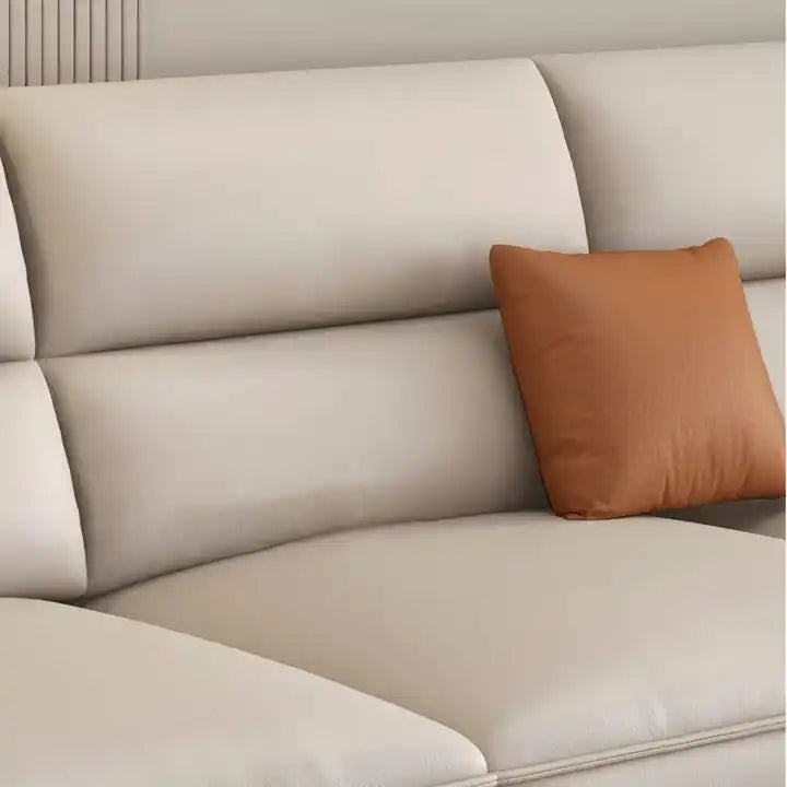 beige l shape leatherette sofa with deep seating, high back cushions and wide padded arms — wide room view showing the com...