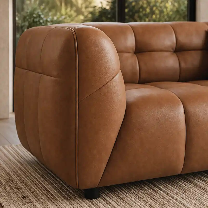 warm brown luxury sofa with deep square cushioning, rounded edges and a low relaxed shape — wide room view showing the com...