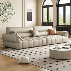 wide leatherette sofa with deep square cushioning and a low relaxed shape — close view showing the colour and material tex...