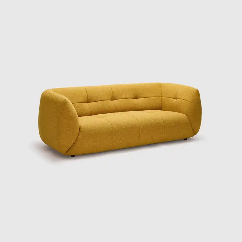 warm mustard rounded sofa with deep square cushioning and a soft textured finish — close view showing the colour and mater...