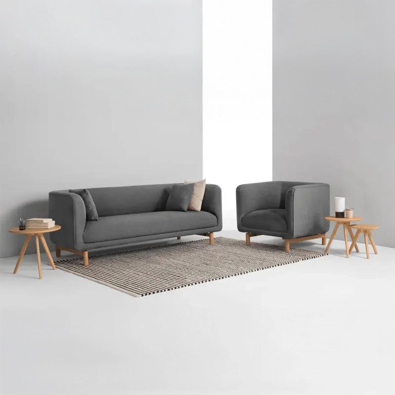 curved fabric sofa with soft wraparound arms, deep cushioning and raised wooden legs — close view showing the colour and m...
