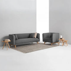 curved fabric sofa with soft wraparound arms, deep cushioning and raised wooden legs — close view showing the colour and m...